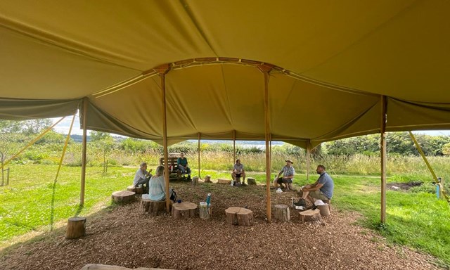 Volunteers sitting on log stumps eating lunch